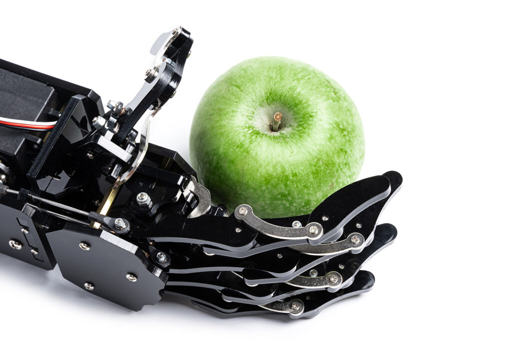 A robotic hand holding green apple is symbolic of Apple Intelligence