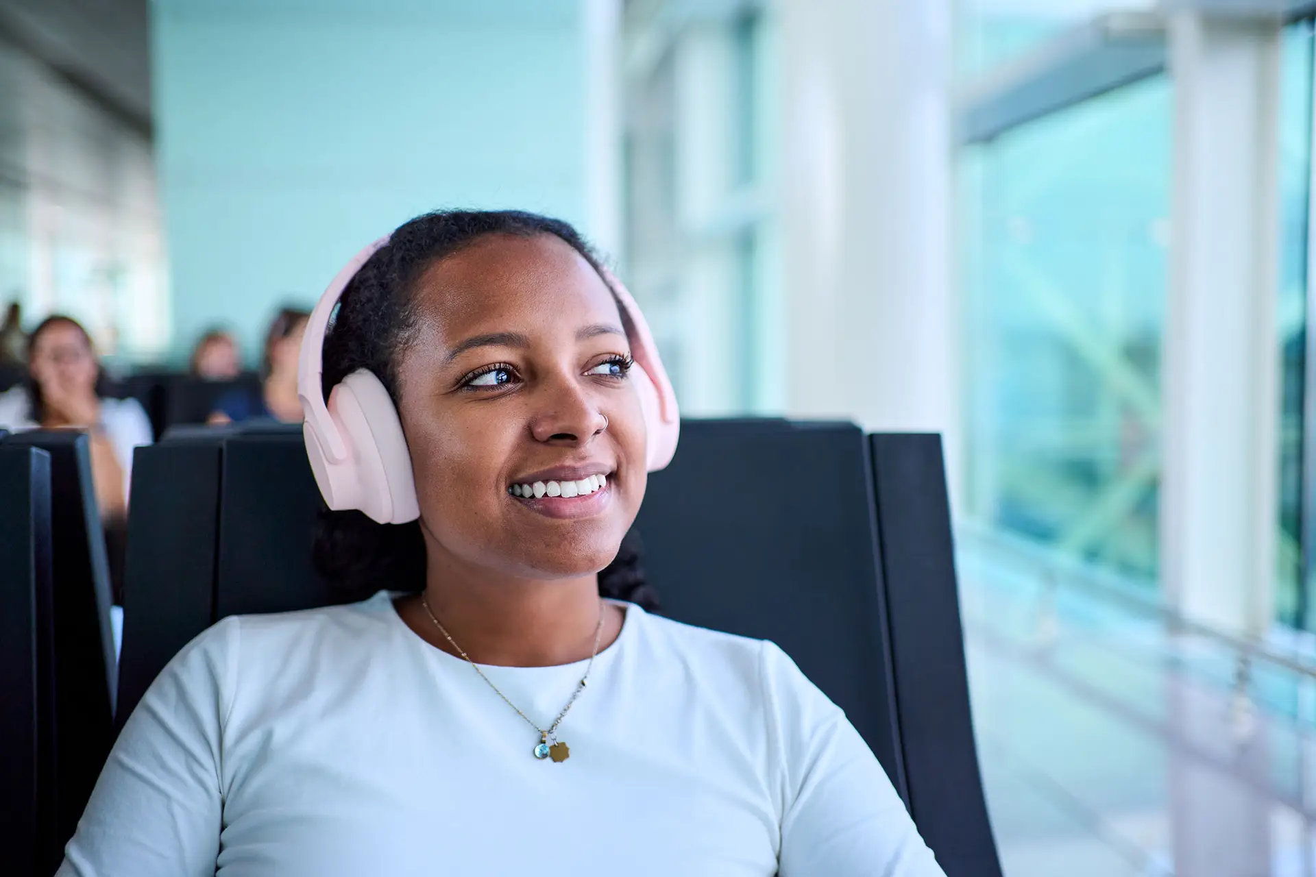 Woman wearing headphones, at the airport, while listening to CML